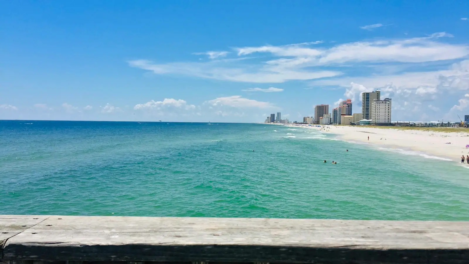 Shallow blue-green sea running up to a line of tall coastal buildings under a clear sky