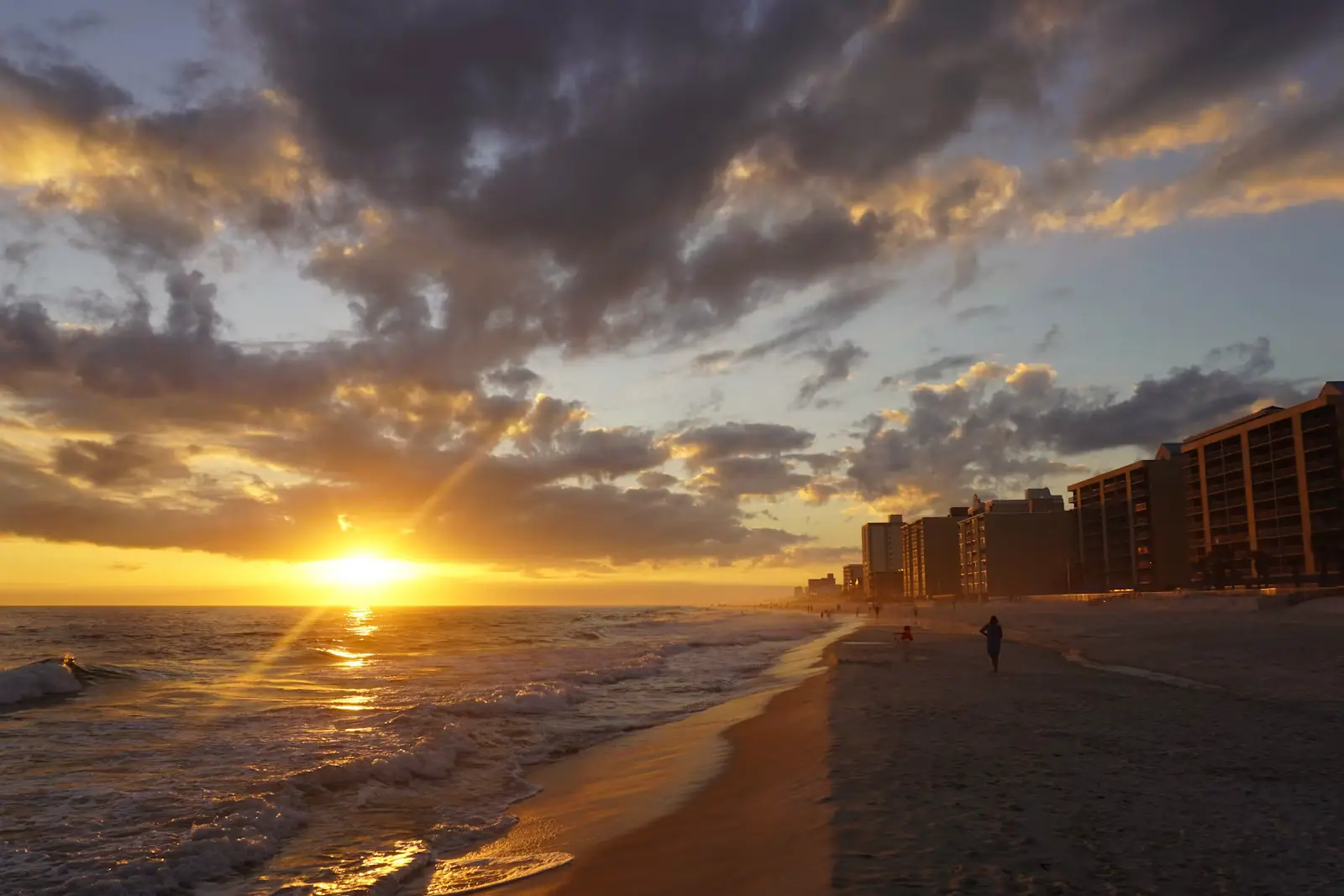 Low evening sun over a wide empty beach with wet sand reflecting the sky
