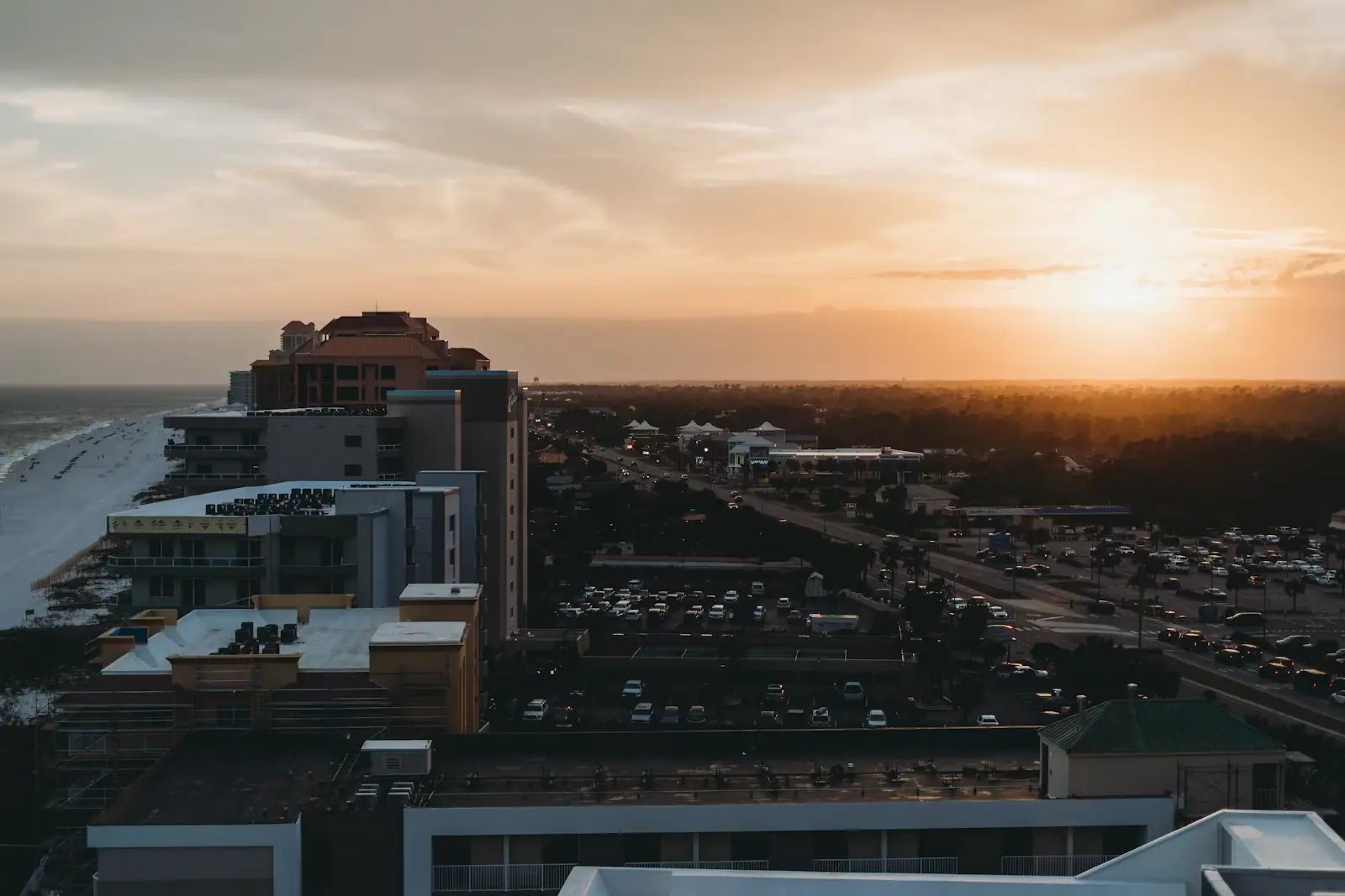 Golden evening light over low buildings and pale sand along the Alabama Gulf coast