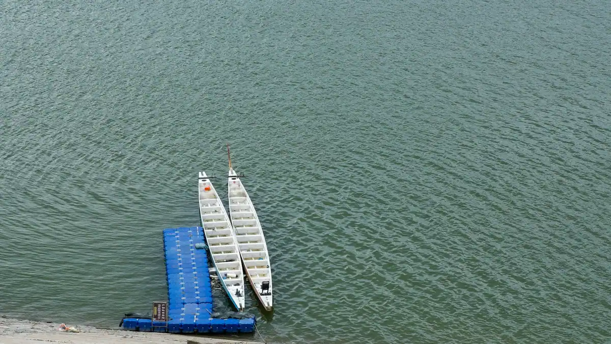 Two white boats moored alongside a floating dock in calm water