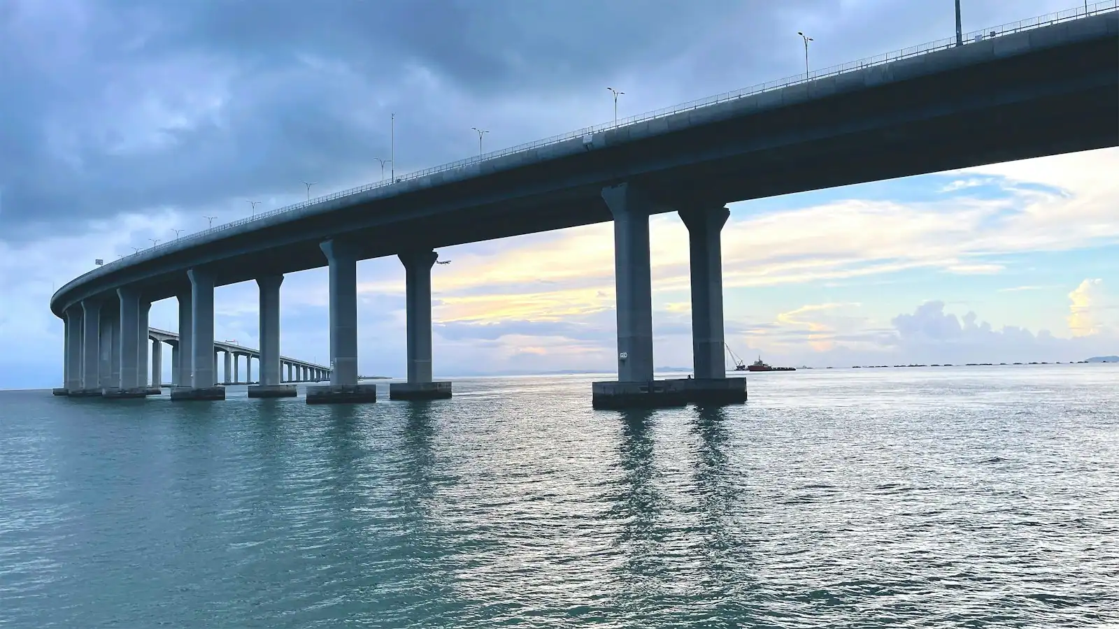 A long low road bridge crossing a wide stretch of open water under a pale sky