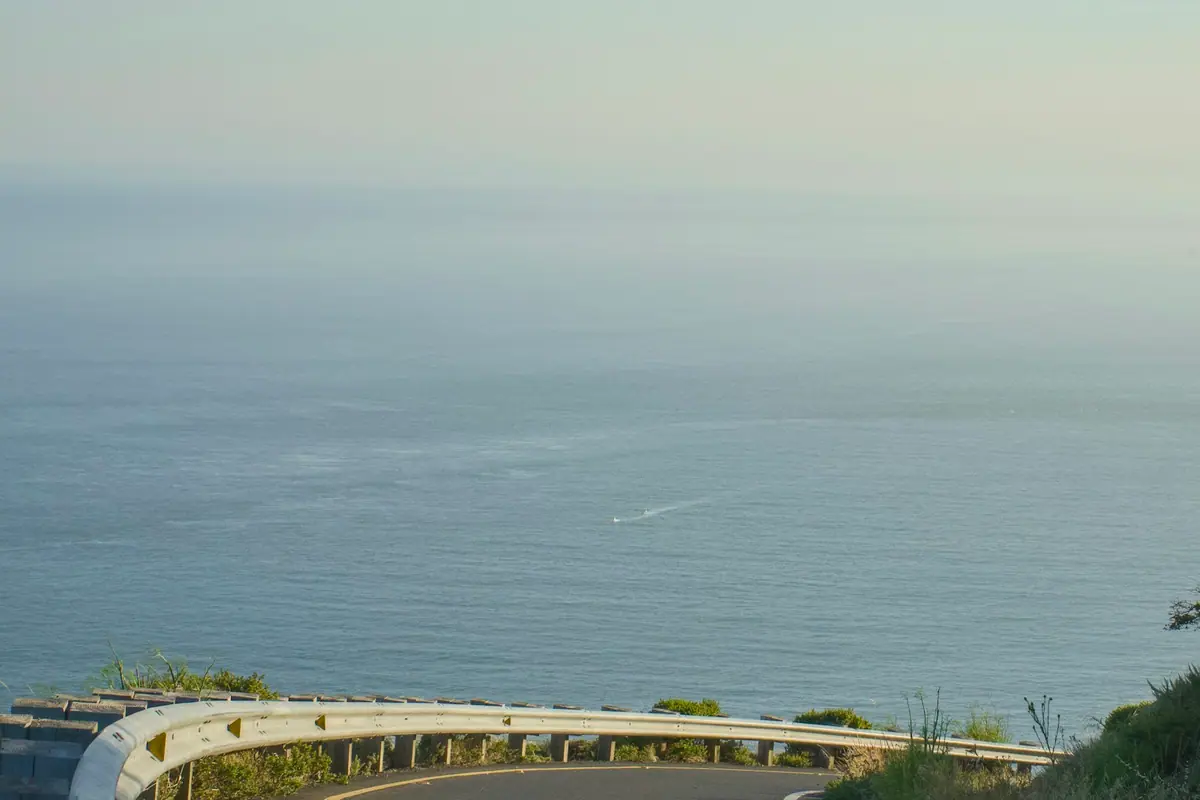 A curving coastal road running beside open water on a clear day
