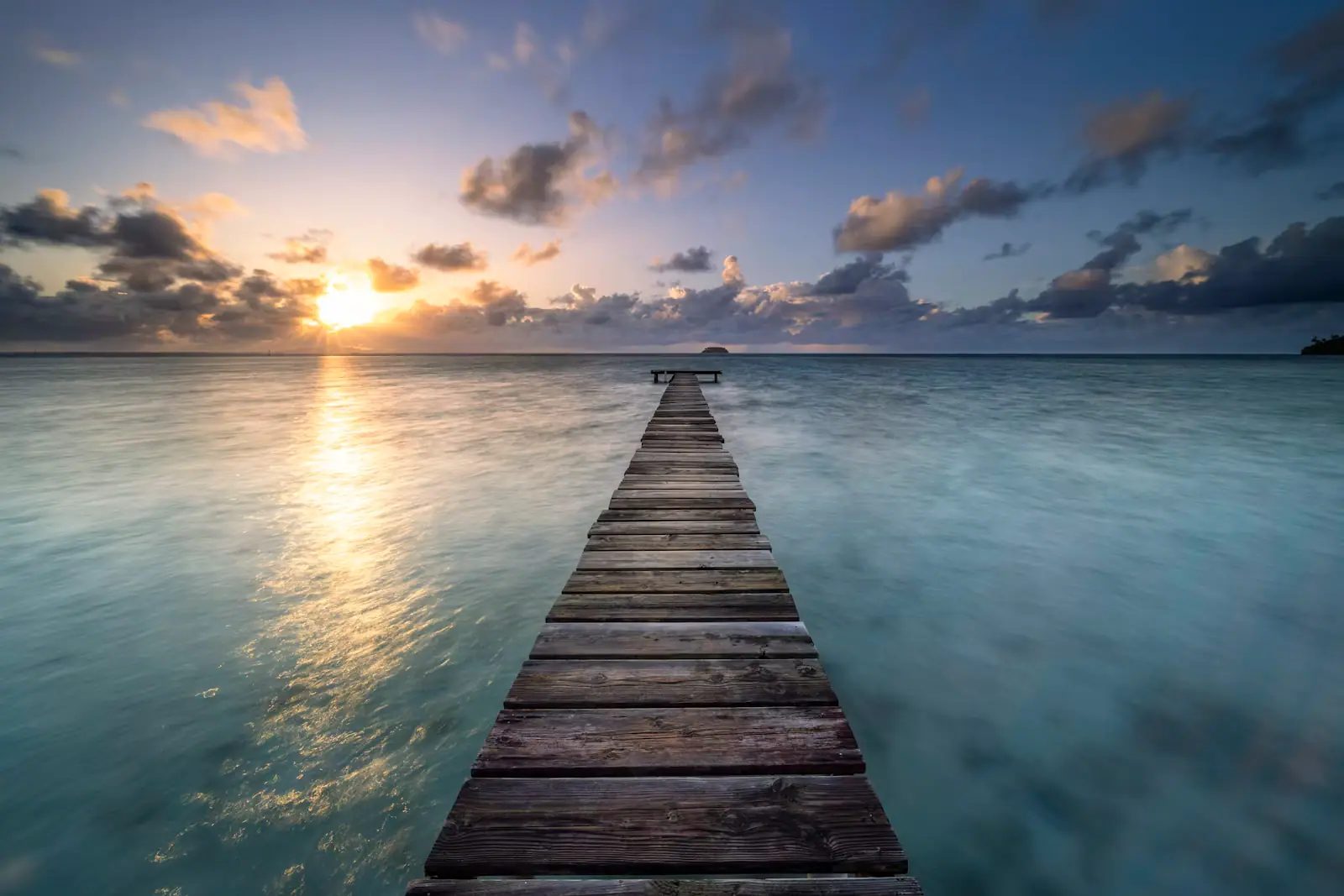 A long pier running out over calm water in low evening light