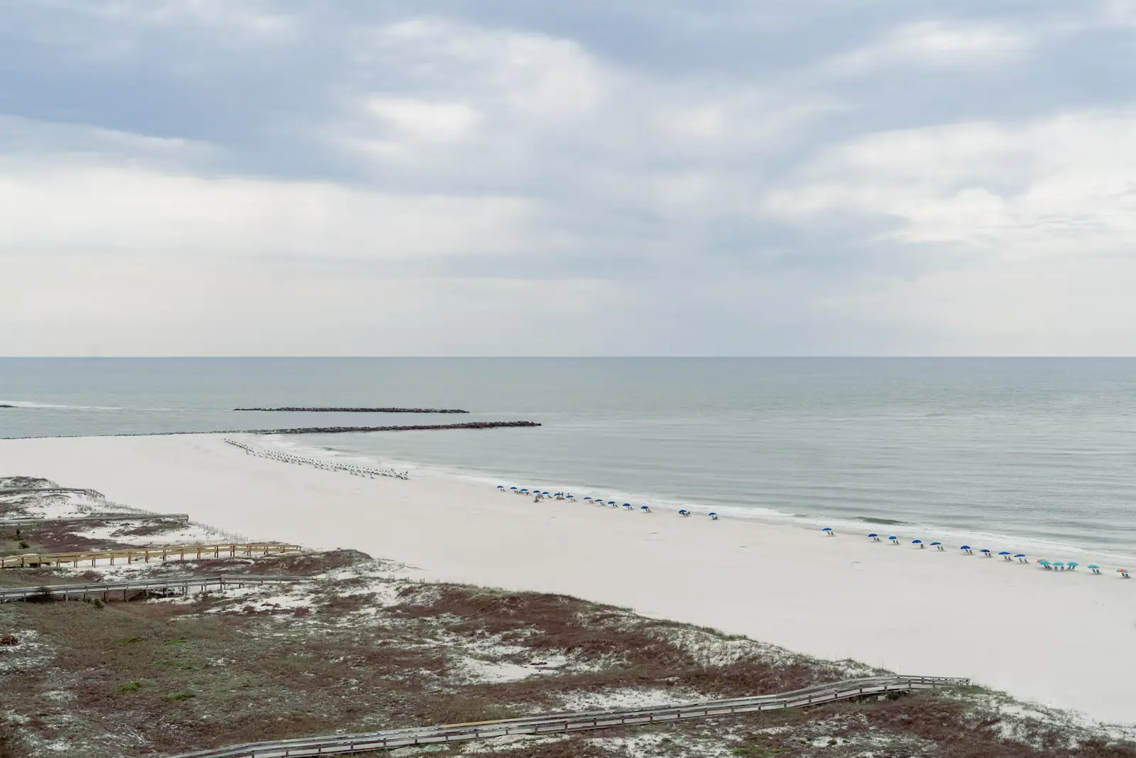 Elevated view along the Alabama coast showing pale sand meeting calm green water on a clear day