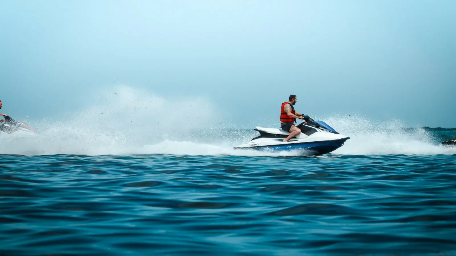 Two people riding personal watercraft across open water