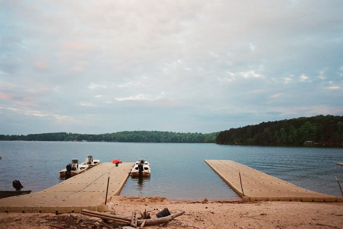 A floating dock and launch ramp on calm water with pines along the far bank