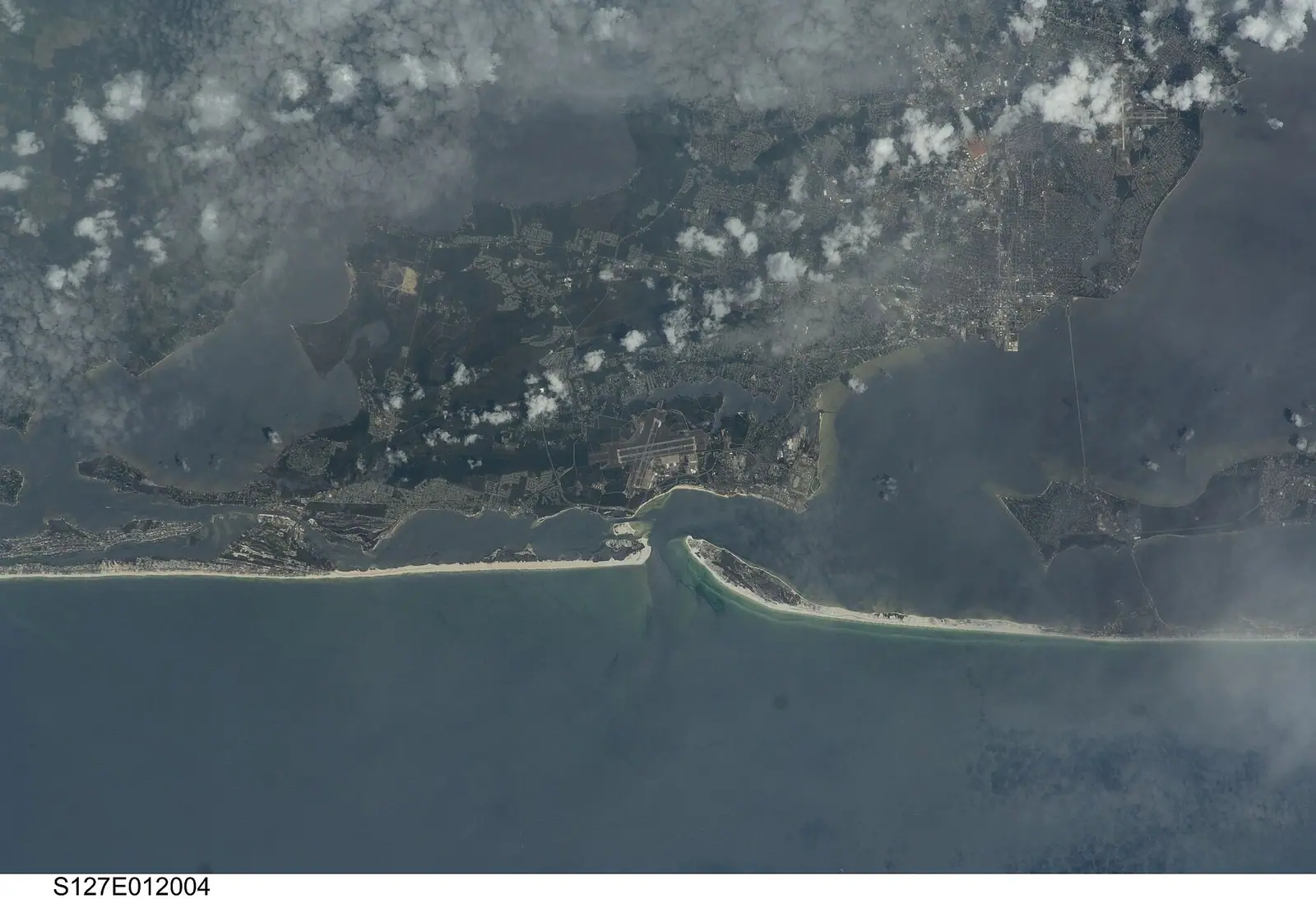 An aerial view of a marina basin ringed by docks, moored boats and low waterfront buildings