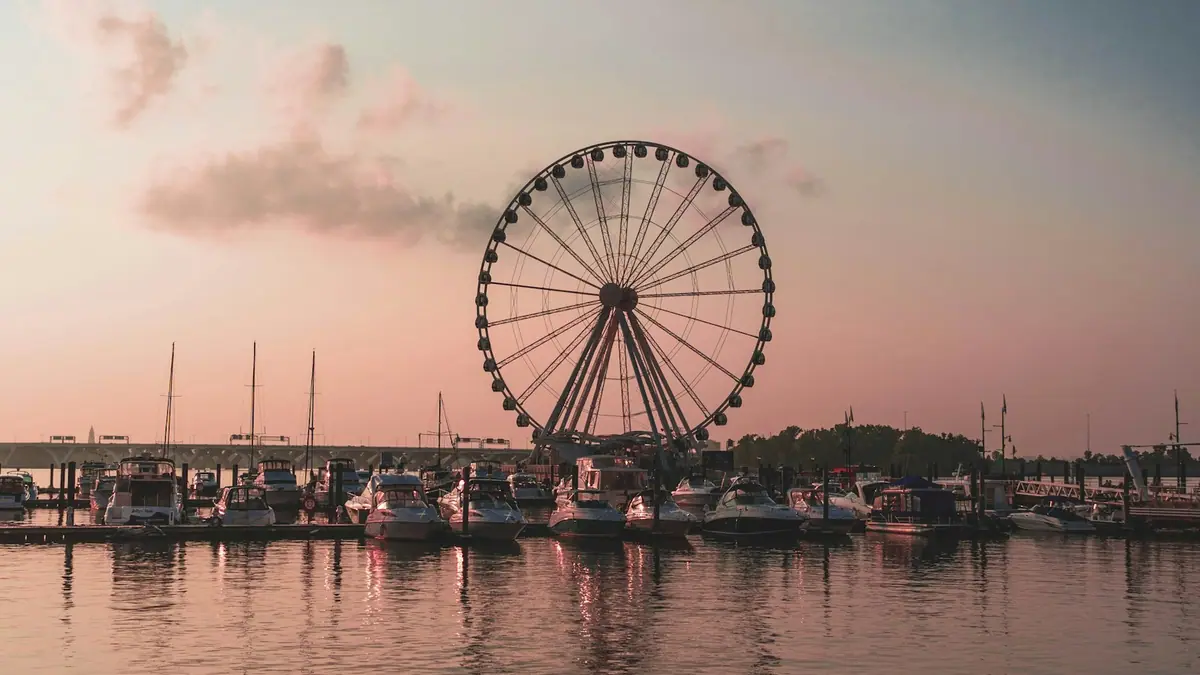 A large Ferris wheel standing beside a body of water under a clear sky